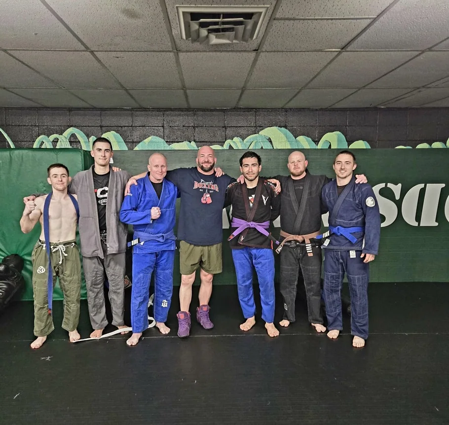 A group of jiu-jitsu practitioners posing together at the gym.