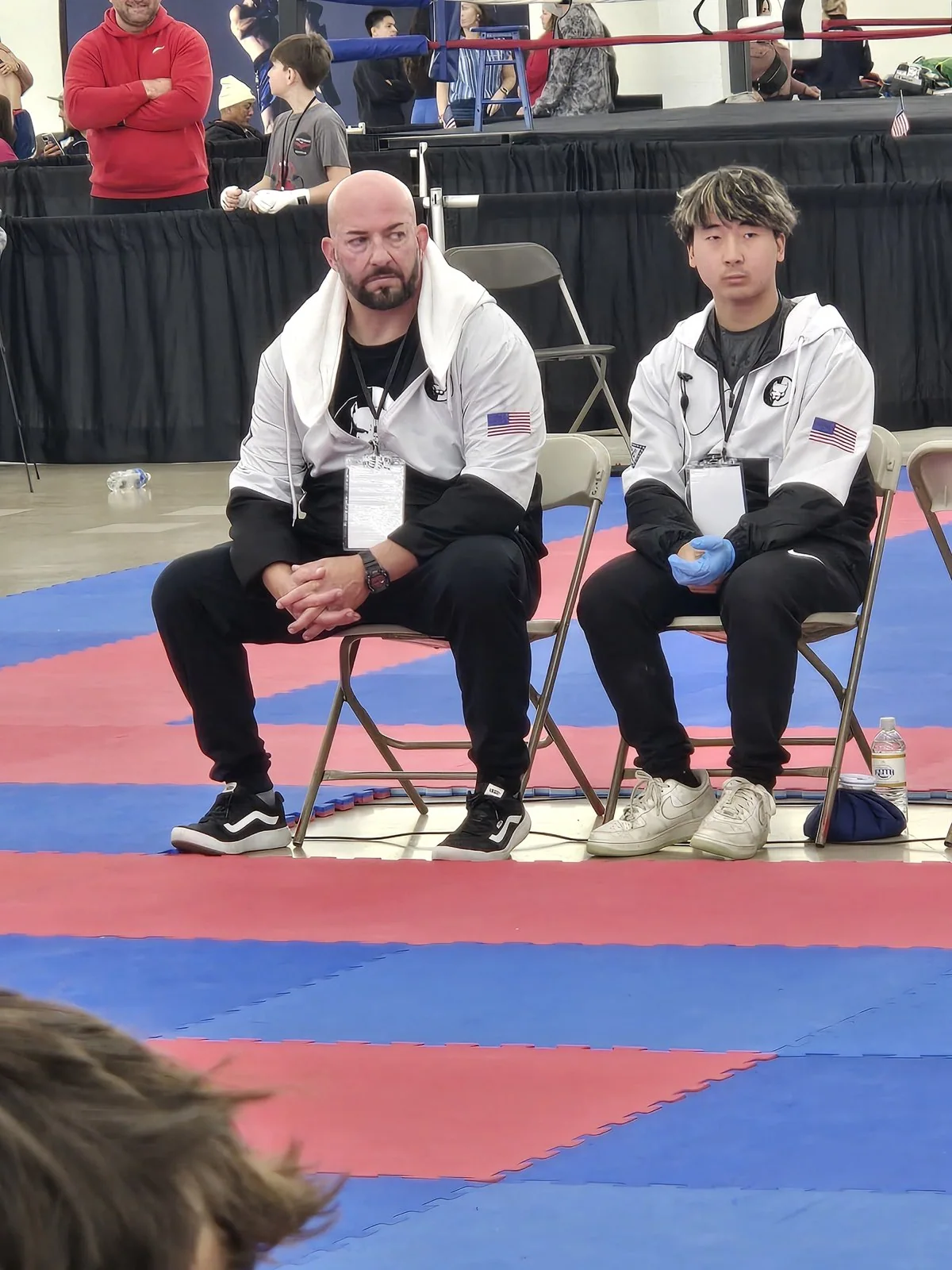 A TCB coach and fighter seated beside the competition mats