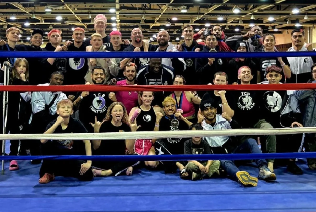 TCB teammates gathered together inside a boxing ring