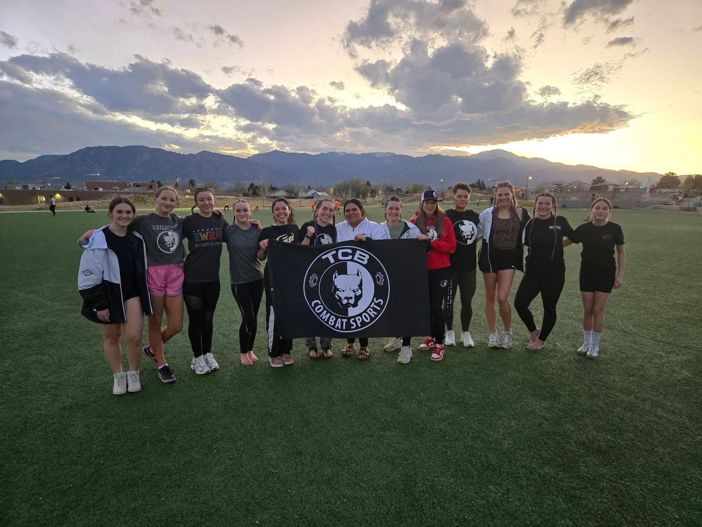 TCB athletes with the team banner in front of a mountain landscape.