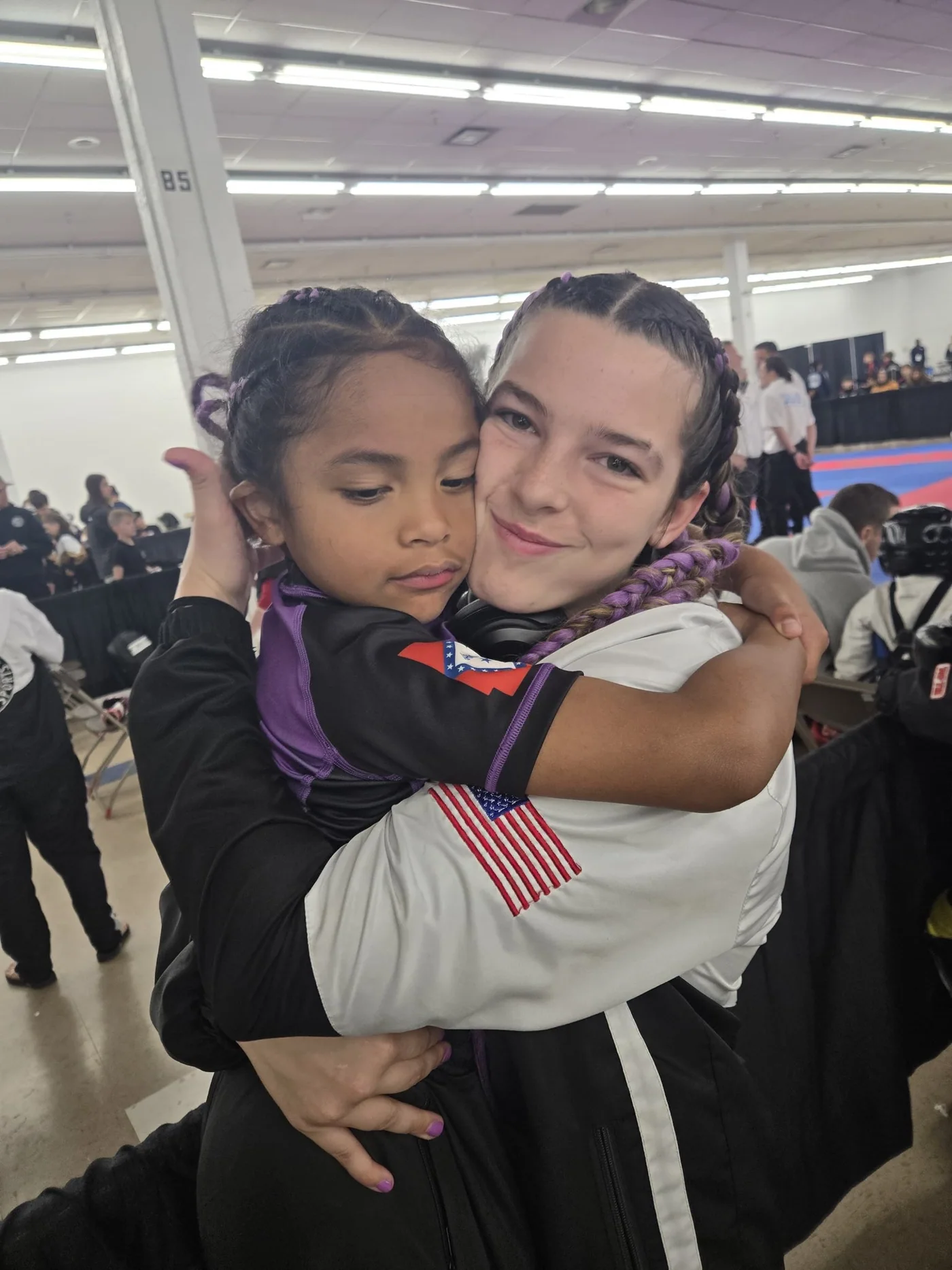 Two young TCB participants share a hug in team colors.